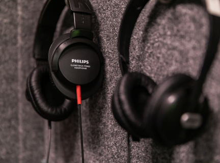 Two pairs of black headphones hanging on a wall