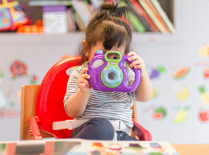 Potograhp showing a toddler with plastic camera