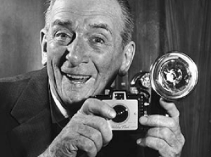 Archival photograph of man holding a camera with flash bulb