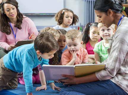 Two adults reading to a group of children